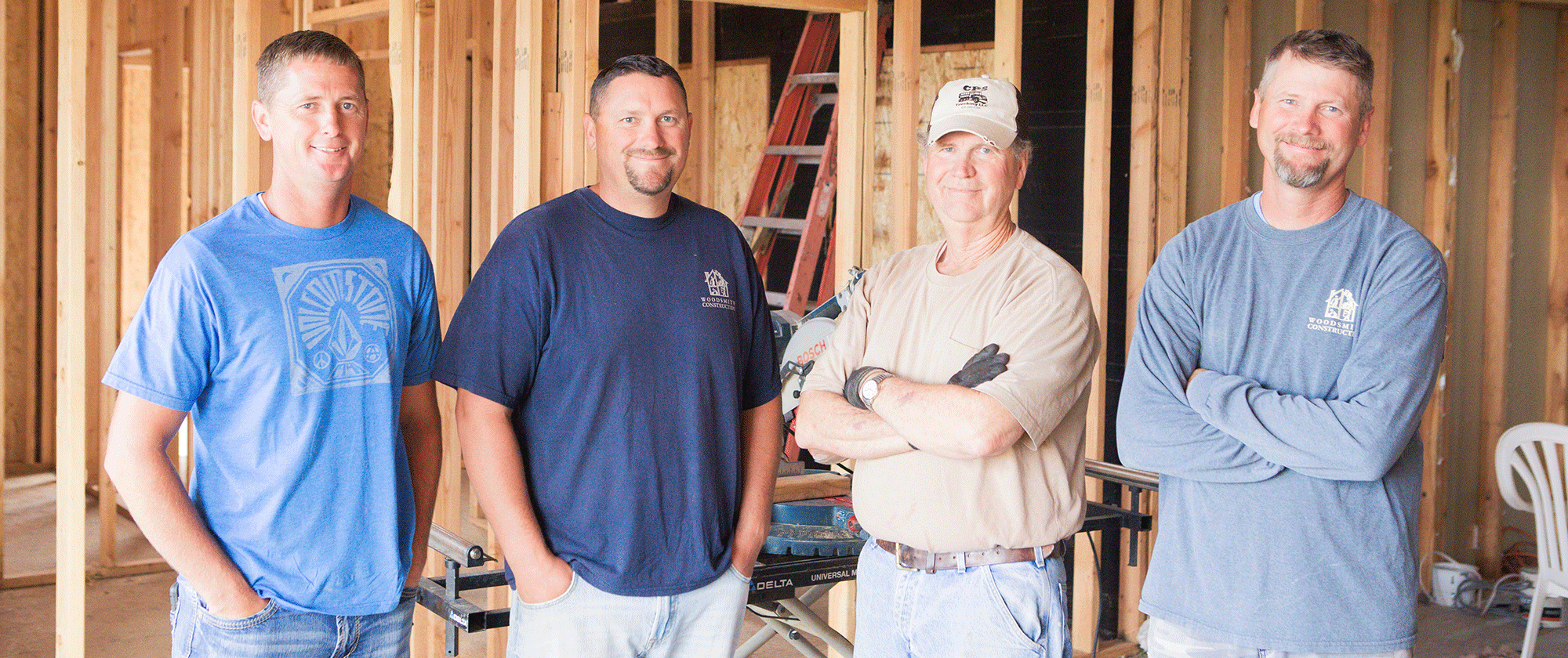 Woodsmith Construction Family Members Mike, Dan, Clyde, and Corey standing in framed house