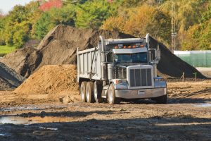 a dump truck about to unload a pile of dirt at an excavation site